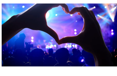 A crowd on the dancefloor forming a heart shape with their hands